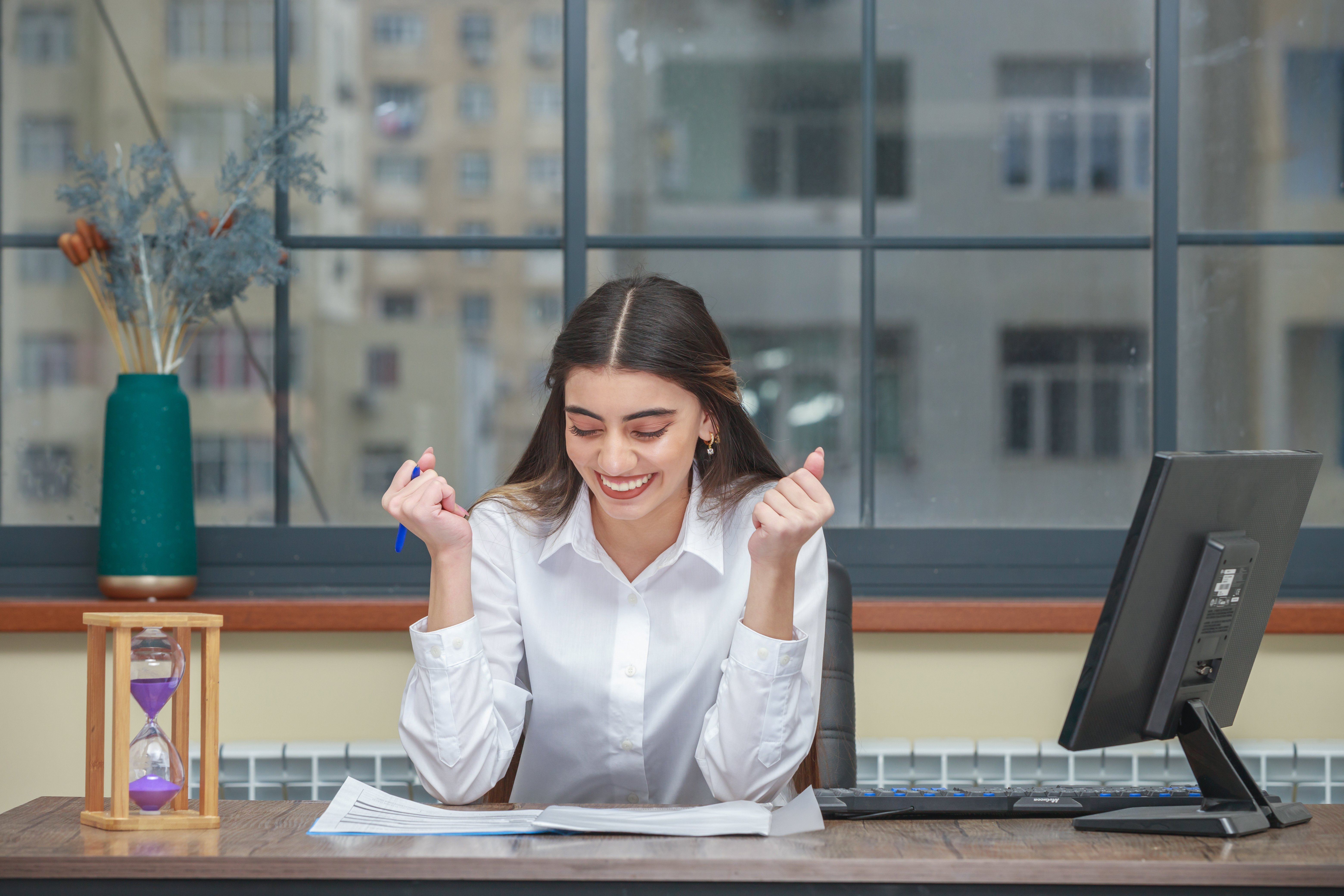 portrait-of-young-businesswoman-sitting-at-the-desk-and-squeeze-her-fists-high-quality-photo